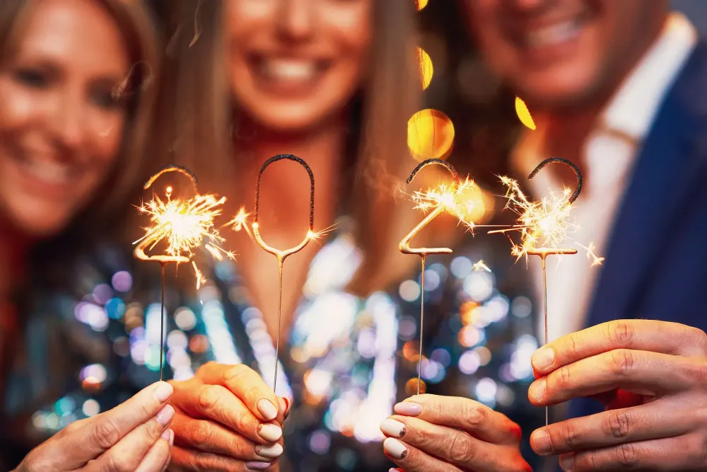 Three people in the background holding 2022 themed sparklers in the foreground